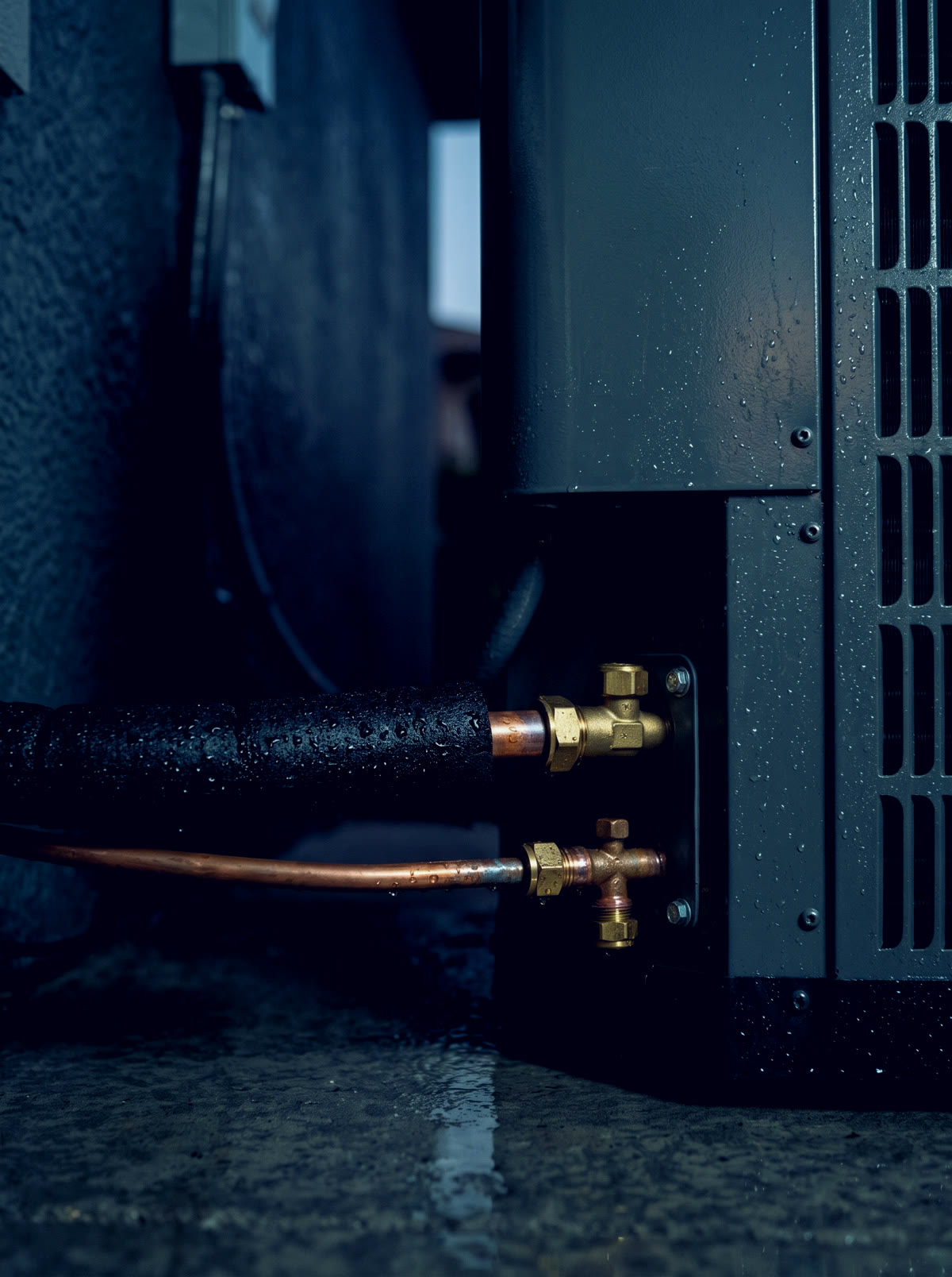 Insulated copper refrigerant lines connected to brass service valves on the side of the unit
